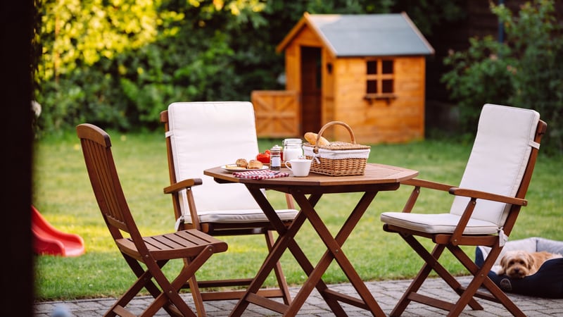 Friedlicher Familien-Hinterhof mit Spielsachen, Picknick-Tisch und Hundebett im warmen Nachmittagslicht — abgesichert mit der Barmenia Privathaftpflicht